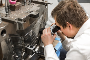 quality engineer checks deficiencies on the injection mold by a microscope, industrial concept