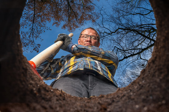 man with a shovel stands by his hole in the garden