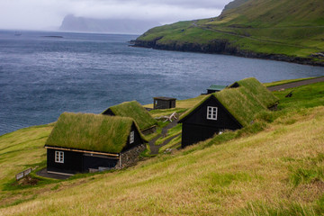 Small black houses with grass on the roof on the shore of the Atlantic Ocean