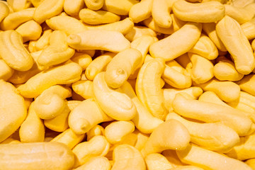 Fresh fragrant pieces of yellow marmalade in the form of bananas are in a large pile on the counter in the store. Beautiful tasty treat made from natural ingredients.