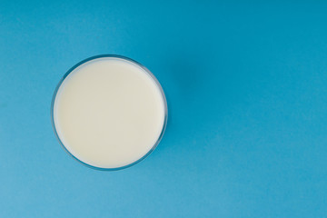 Glass of milk on the blue background. Top view.