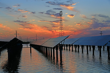 Obraz premium Solar photovoltaic panels in the water, in the sunset sky background