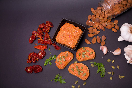 Tostadas con sobrasada vegana e ingredientes sobre fondo negro. 