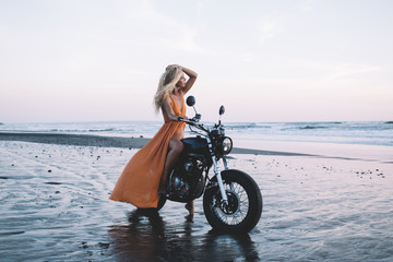 Tender young woman enjoying views on motorbike at seashore