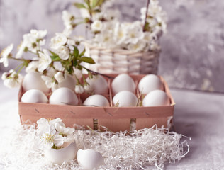 Easter still life. Gentle light photo. White eggs and delicate spring flowers of cherry and peach.