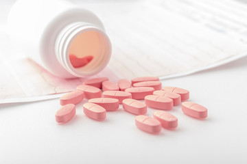 Ischemic heart disease pills from medicine white bottle and cardiogram on white background with...