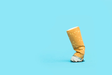Cigarrillo apagado sobre fondo liso azul. Vista de frente y de cerca macro. Copy space. Concepto:...