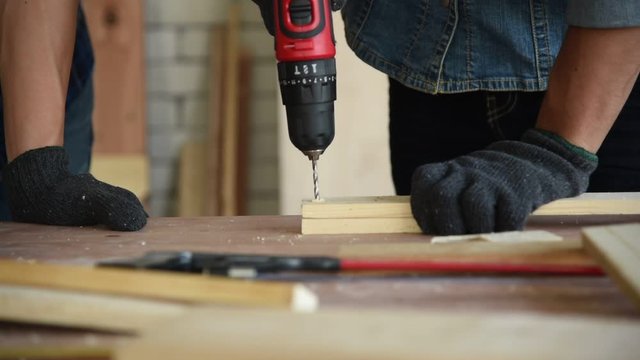 Young Asian group man worker using electric hand drill to build diy wood furniture in workshop