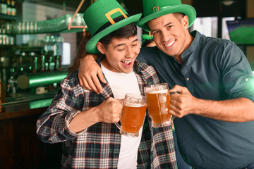 Young friends with beer celebrating St. Patrick's Day in pub