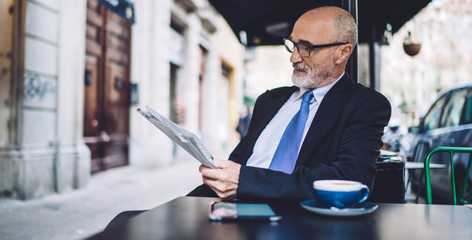 Elegant executive reading newspaper at sidewalk cafe