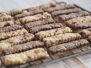 Homemade shortbread puff pastry chocolate cookies on a wooden background. On a grate for cooling.
