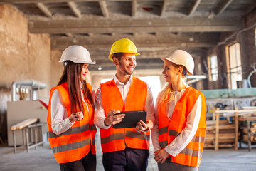 Team of young construction workers discussing project details with executive supervisor