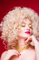 Beautiful fashionable blonde girl in retro style with voluminous curly hairstyle, bare shoulders and a gold necklace