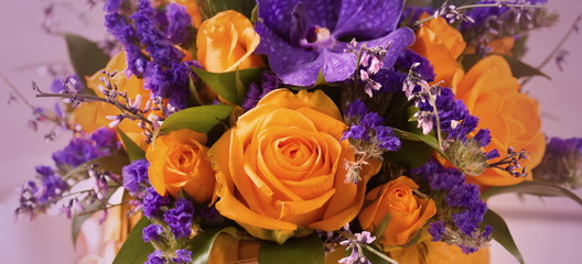 Close-up of a beautiful spring bouquet with bright orange roses and purple orchids. Beautiful background, photo Wallpaper. Space for text