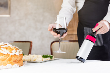 Fototapeta premium Man holding wine and decorated bread on table for celebration a saint in Orthodox faith. Serbian traditional and cultural heritage.