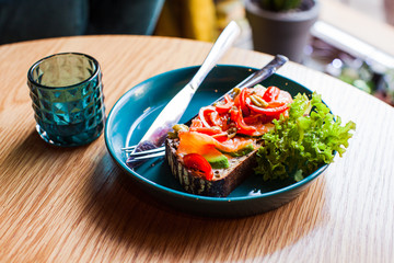 Healthy breakfast. Avocado toast with salmon on blue ceramic plate
