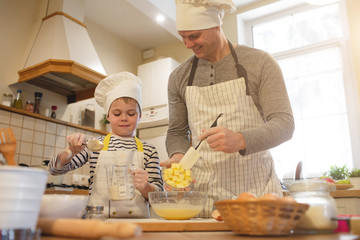 Dad and son in chef's hats are cooking