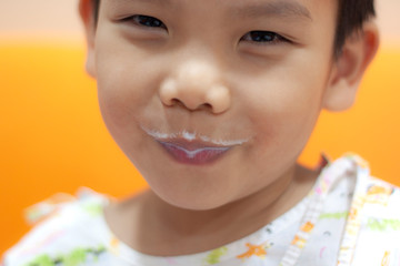 Cute Asian boy is smiling and milk on his mouth.