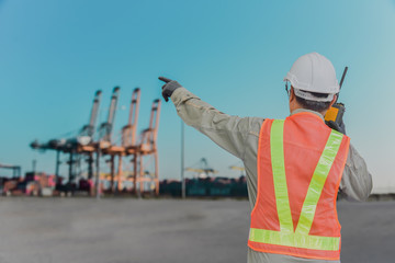 Engineer hand holding radio communication or Walkie Talkie and hand finger pointing on crane in...