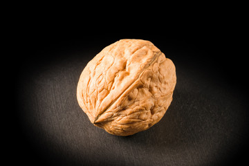 Still life with a whole walnut on black background.