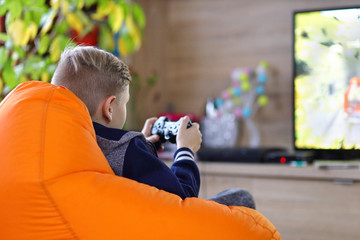 Little boy playing online car racing game at home on new gaming console and smart tv