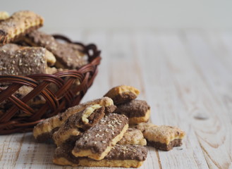 Homemade sandwich puff pastry chocolate cookies in a wicker natural basket of vines. Wooden ancient table.