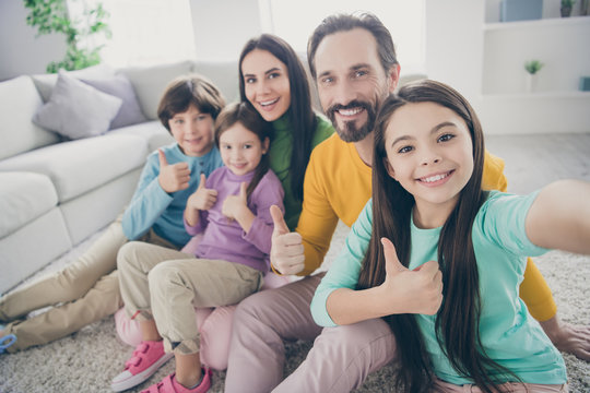 Self-portrait of nice attractive lovely glad big full cheerful cheery family pre-teen kids mom dad showing thumbup at light white interior style house apartment living-room