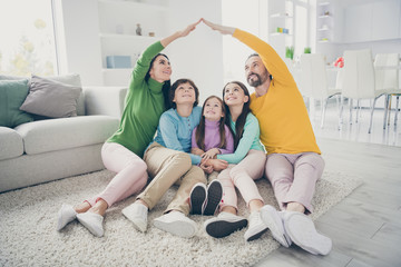 Portrait of nice attractive dreamy careful cheery family three pre-teen kids sitting on carpet...