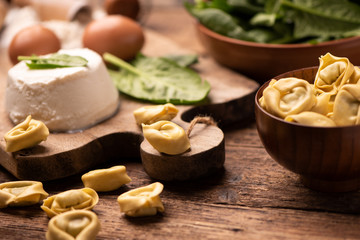 Fesh tortellini ravioli on wooden rustic table with spinach and ricotta