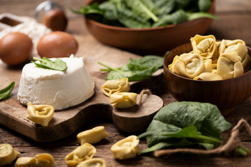 Fesh tortellini ravioli on wooden rustic table with spinach and ricotta