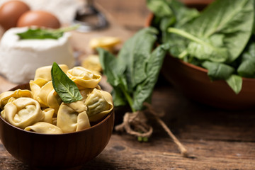 Fesh tortellini ravioli on wooden rustic table with spinach and ricotta