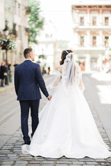 A loving wedding couple are walking back along the streets of the city of Lviv