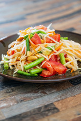 Traditional Thai food papaya salad prepared with fine slices of papaya, tomatoes, green beans and peanuts.