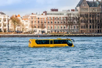 Fotobehang Attraction in Rotterdam, an amphibious vehicle in the river "de Maas" that can travel by road and sail like a boat with the appearance of a coach or bus © Hulshofpictures