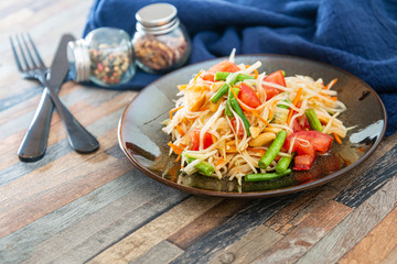 Traditional Thai food papaya salad prepared with fine slices of papaya, tomatoes, green beans and peanuts.