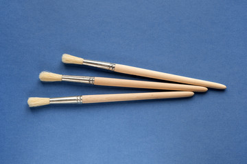 Set artistic paint brushes isolated on blue background. Tool for the artist. Painting background. Copy space, flat lay. Art, creativity and people concept. Color of the year 2020 classic blue.