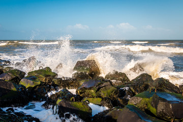 Pier at corner of Holland, with basalt blocks and splashing and foamy North Sea water in the winter time.