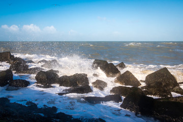 Pier at corner of Holland, with basalt blocks and splashing and foamy North Sea water in the winter time.