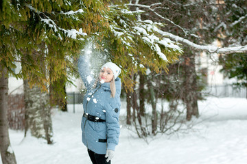 winter mood. Woman in a white cap. Walk December December February. Snowy tree spruce branches park walk. Beautiful girl in a blue down jacket. Place for a text banner. dream fairy tale