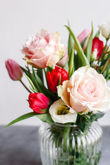 Spring bouquet in transparent glass vase. Roses, tulips and lisianthus.