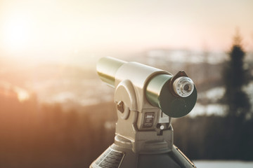 Future and inspiration concept: Tourist binocular, winter landscape and sunshine in blurry background.