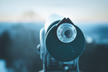 Future and inspiration concept: Tourist binocular, landscape in blurry background. Wintertime