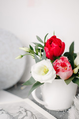 Spring bouquet in white vase on wooden white stand. Roses, tulips and lisianthus.