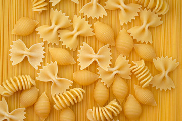 Macaroni closeup top view. Hard pasta of different shapes, bows, spirals and shells on a background...
