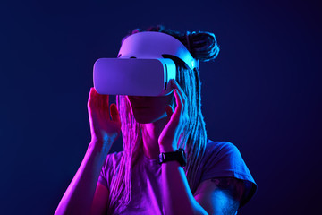 Woman is using virtual reality headset. Neon light studio portrait.