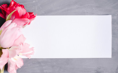 Blank paper copy space. Frame with flowers. Silk ribbon. Gray background. Simple bouquet. Greeting card.