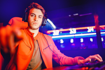 Professional video gamer playing online games tournaments pc computer with headphones, Blurred red...