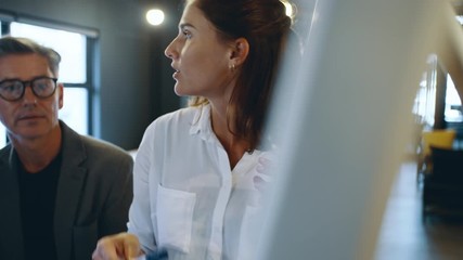 Business associates having a brainstorming session together in front of a white board. Businesswoman explaining the plan to team on a whiteboard in office. - Powered by Adobe