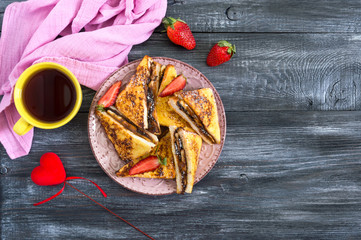 Sweet french toasts with banana, chocolate, strawberries on a wooden background. Tasty breakfast. Top view