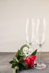 Composition with glass for champagne. Flowers and hearts on grey concrete background.